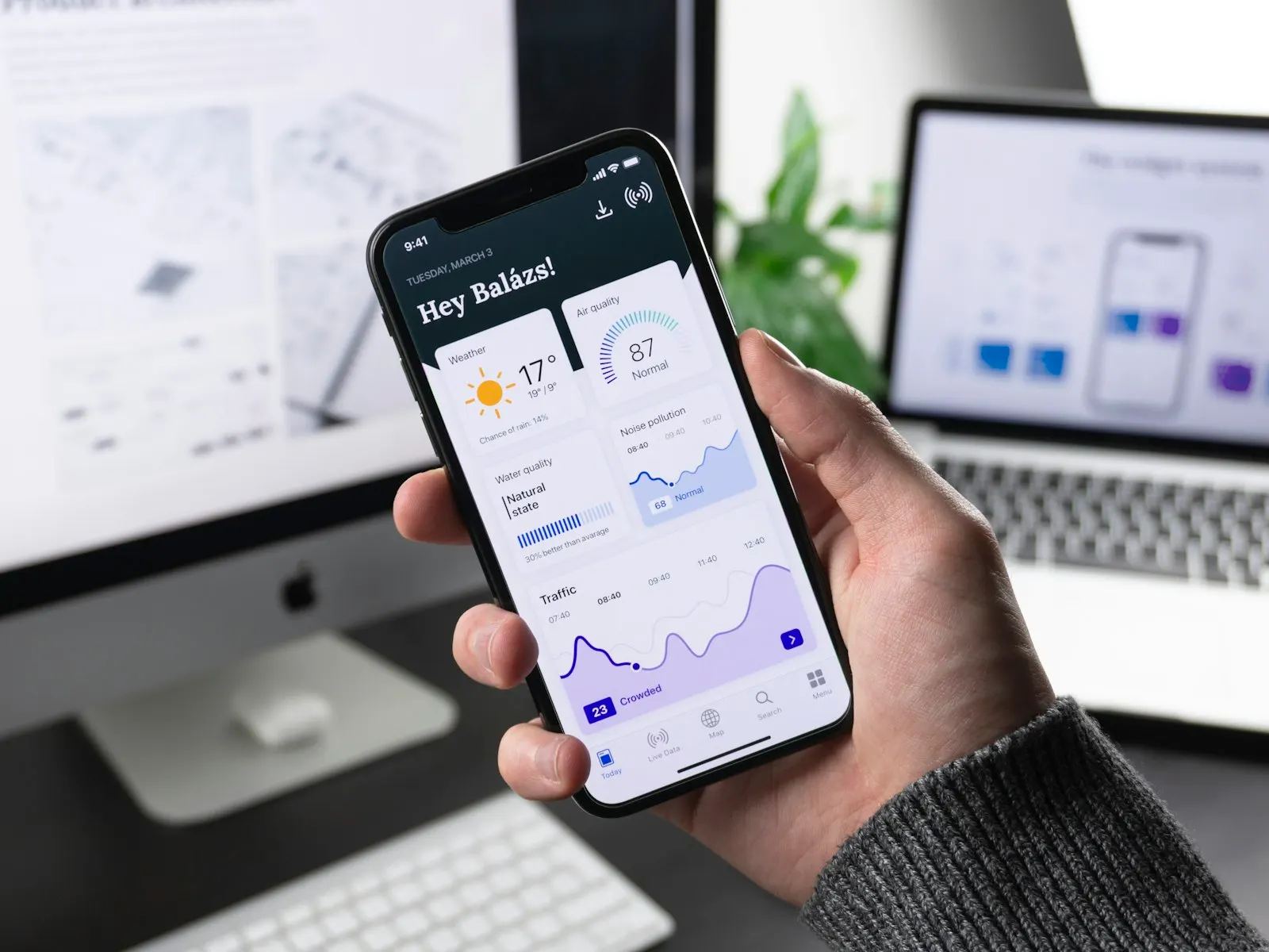 En hand som håller en mobil med en app i en designstudio